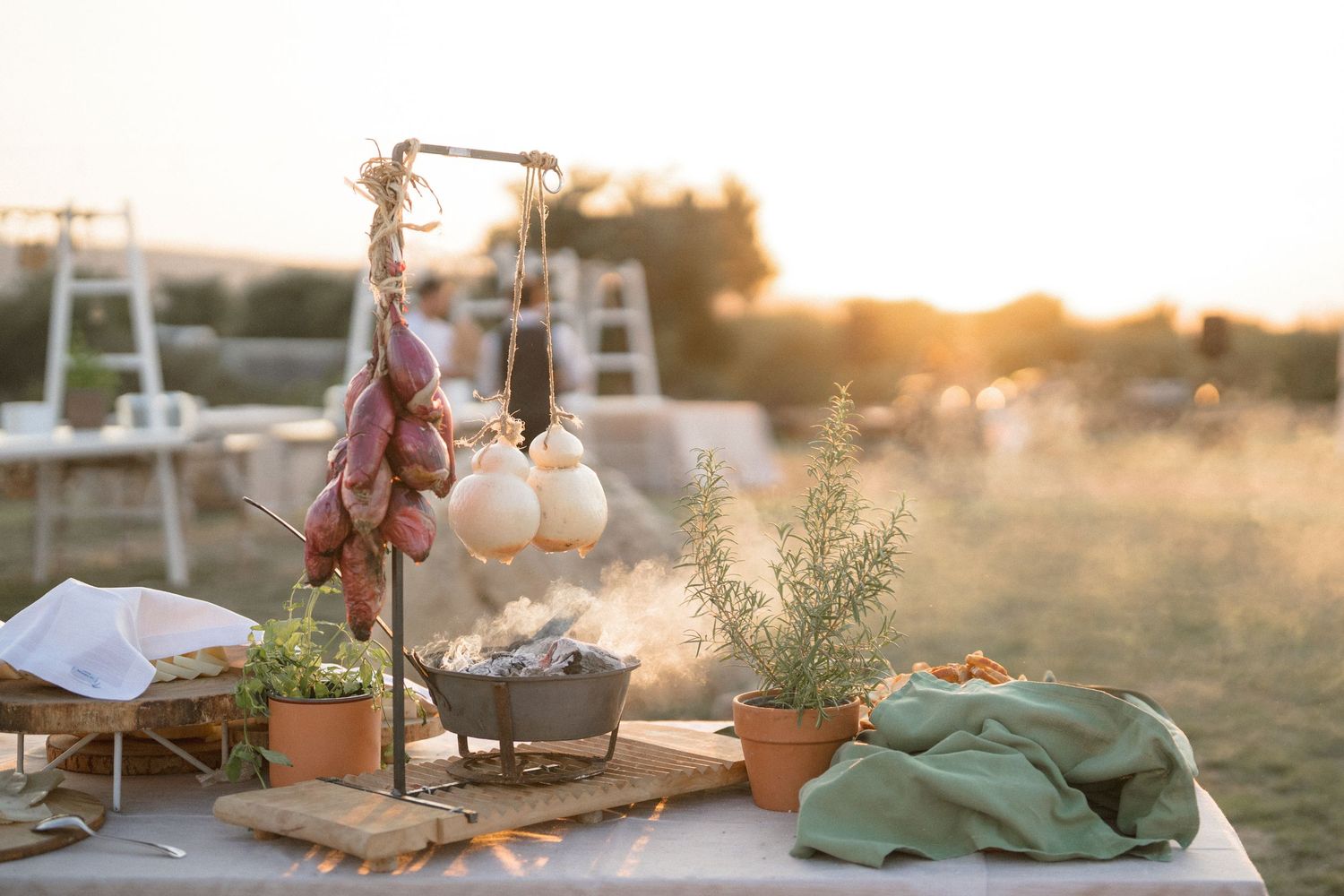 Romantic outdoor wedding decor with hanging florals and candles at sunset.