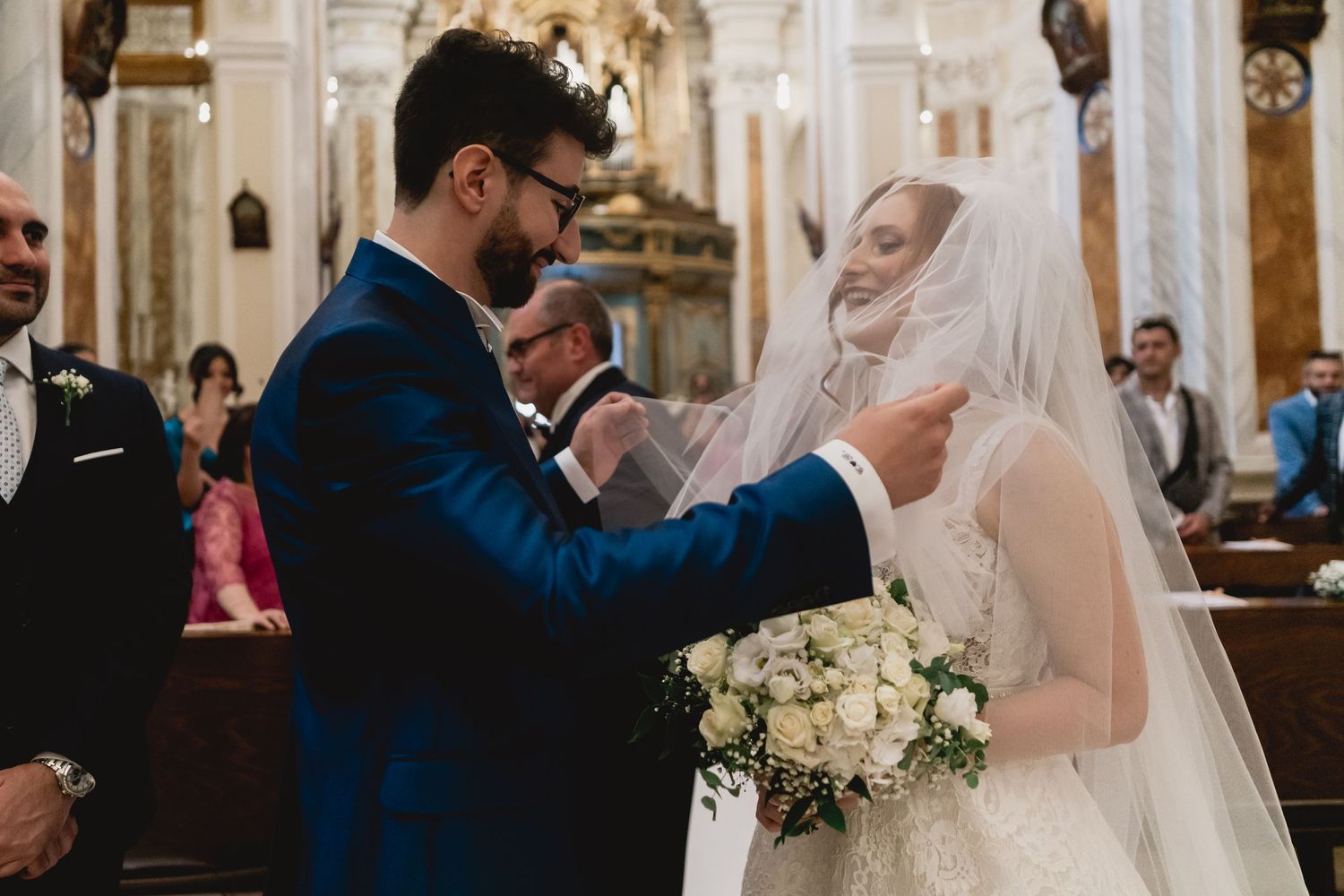 Traditional wedding ceremony taking place at altar in ornate church interior.