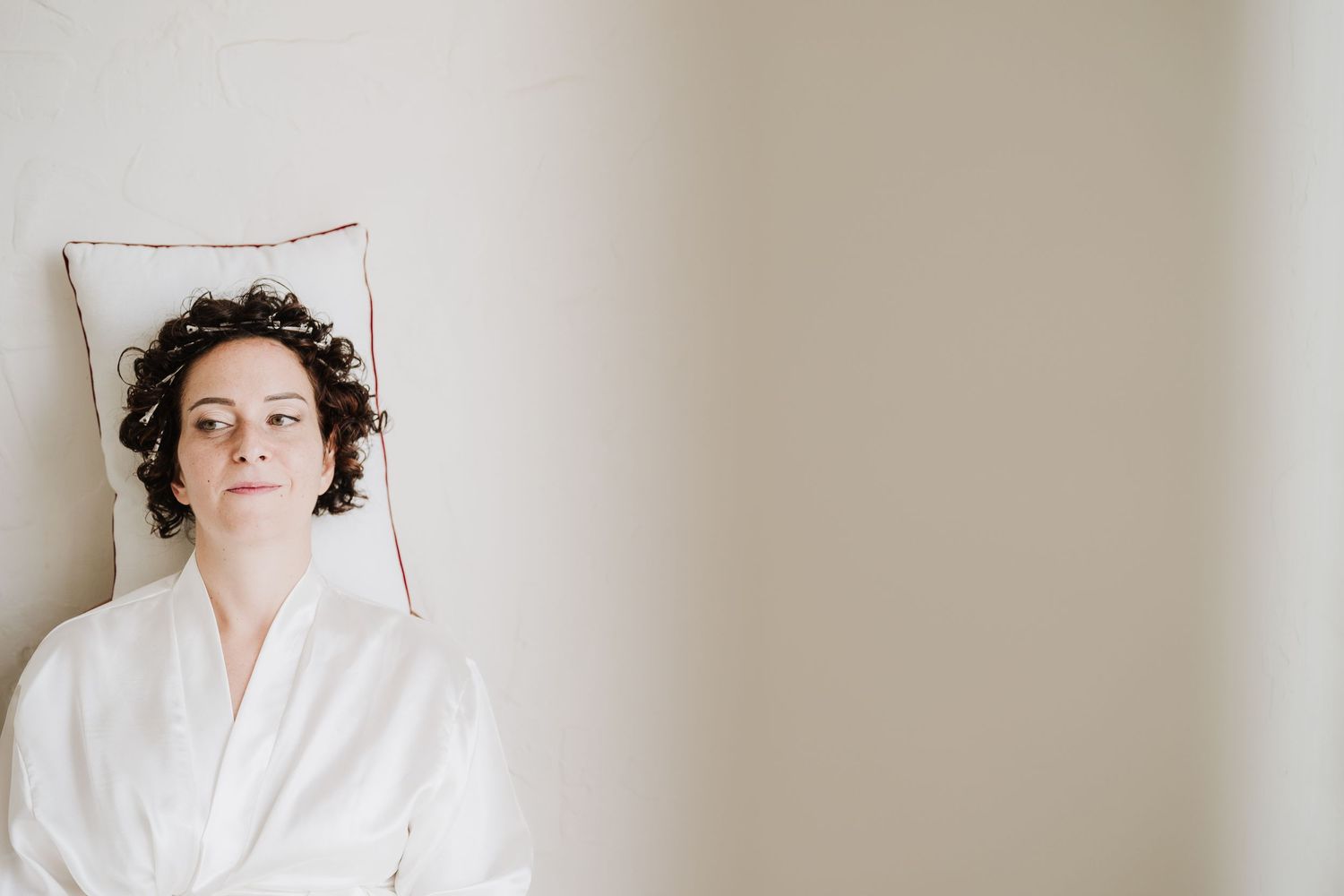 A relaxed figure in a white bathrobe leaning against a light-colored wall.