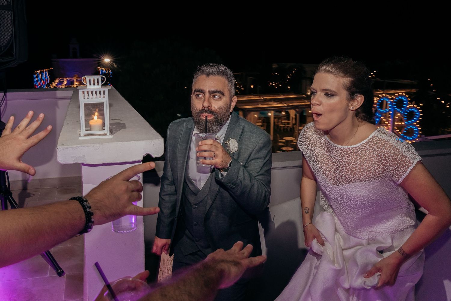 Wedding celebration with guests enjoying drinks and dancing at night.