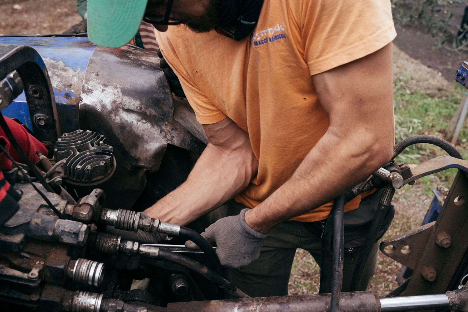 Person in orange shirt performing maintenance work on motorcycle engine parts.