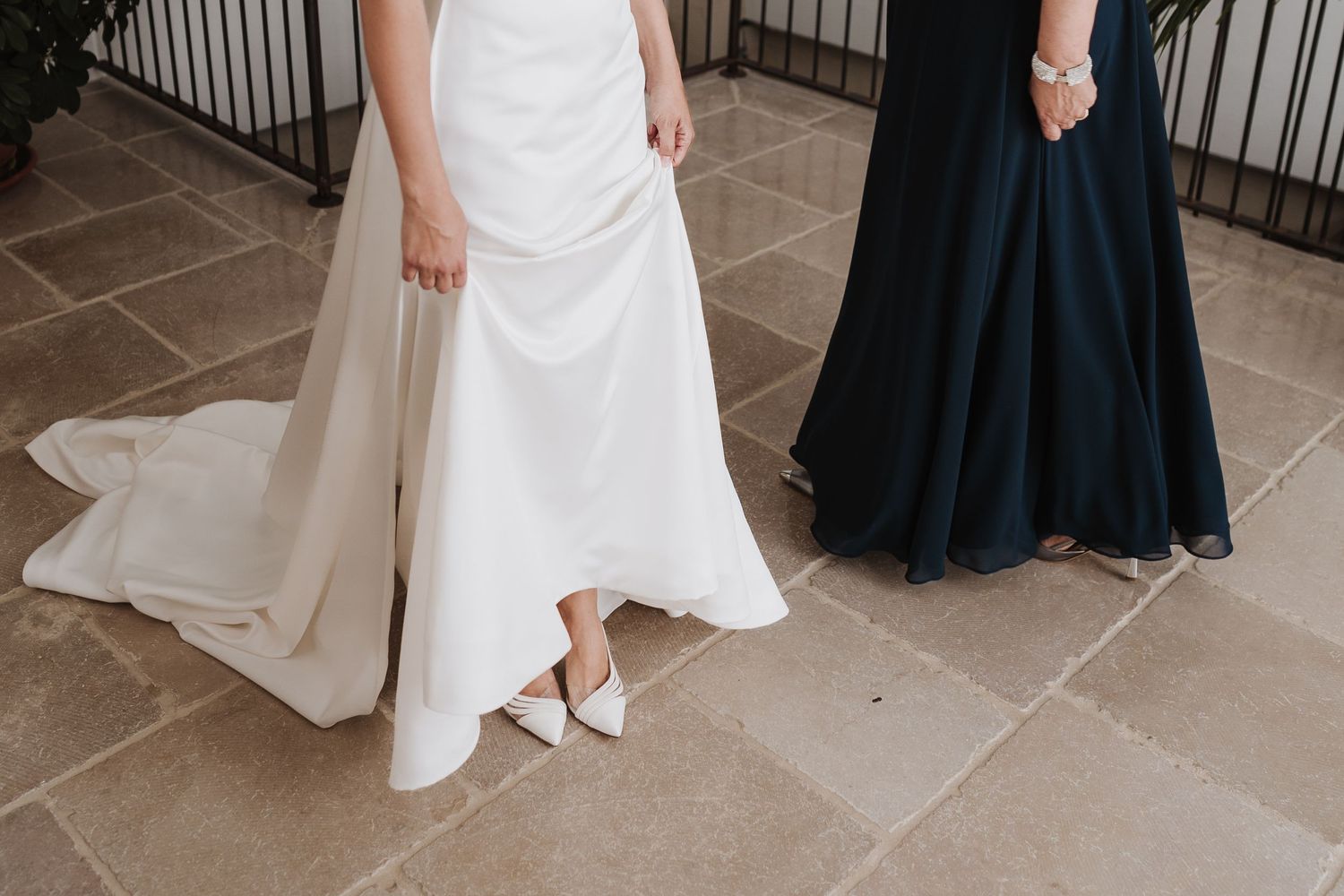 Two formal dresses, one white and one navy, shown from waist down on tile floor.