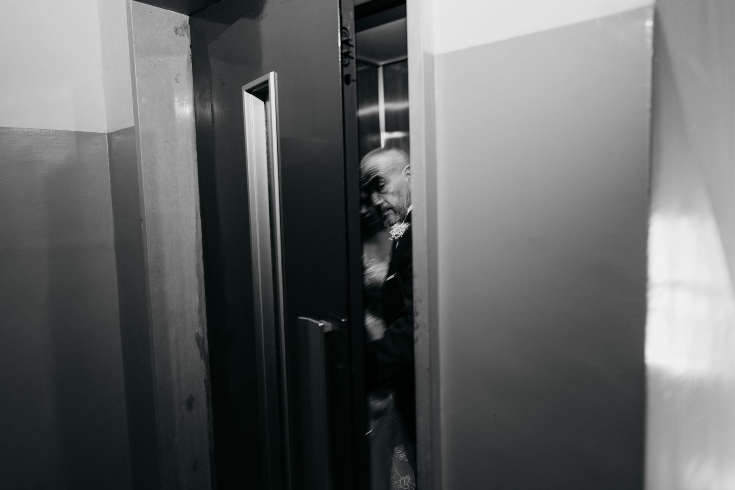 A dramatic black and white photo of someone peeking through a doorway.