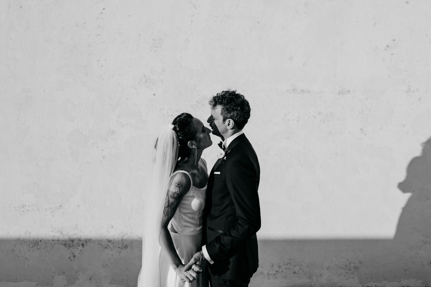 A romantic black and white wedding photo series showing intimate moments between newlyweds against a light background.