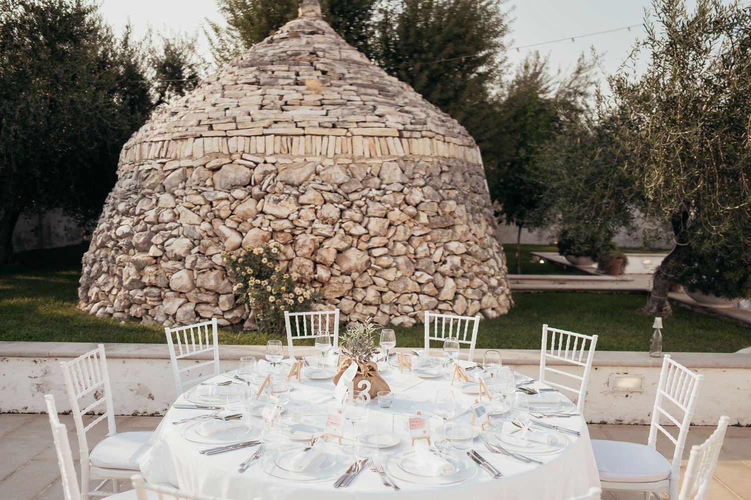 Elegant wedding reception table setting under a rustic stone dome structure.