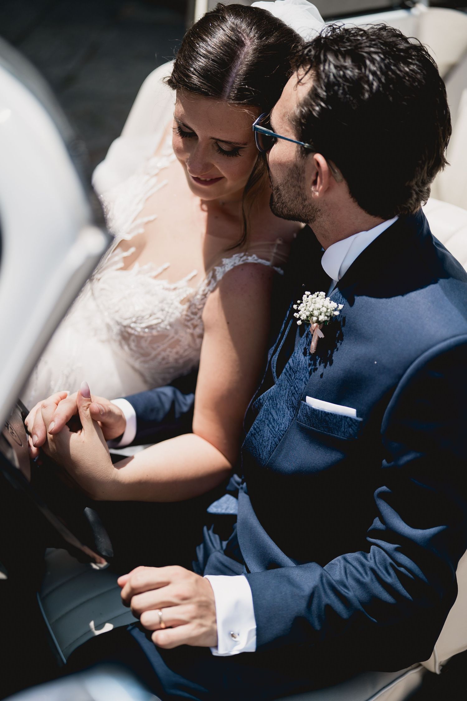 An intimate moment shared between newlyweds in formal attire inside a car.
