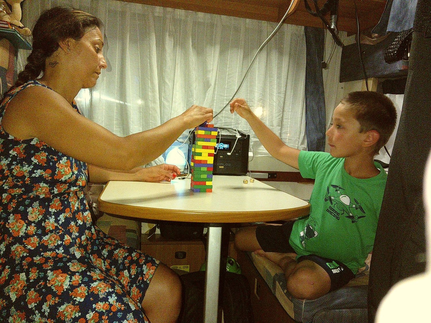 Family moment playing a game at a small round table inside what appears to be a camper.