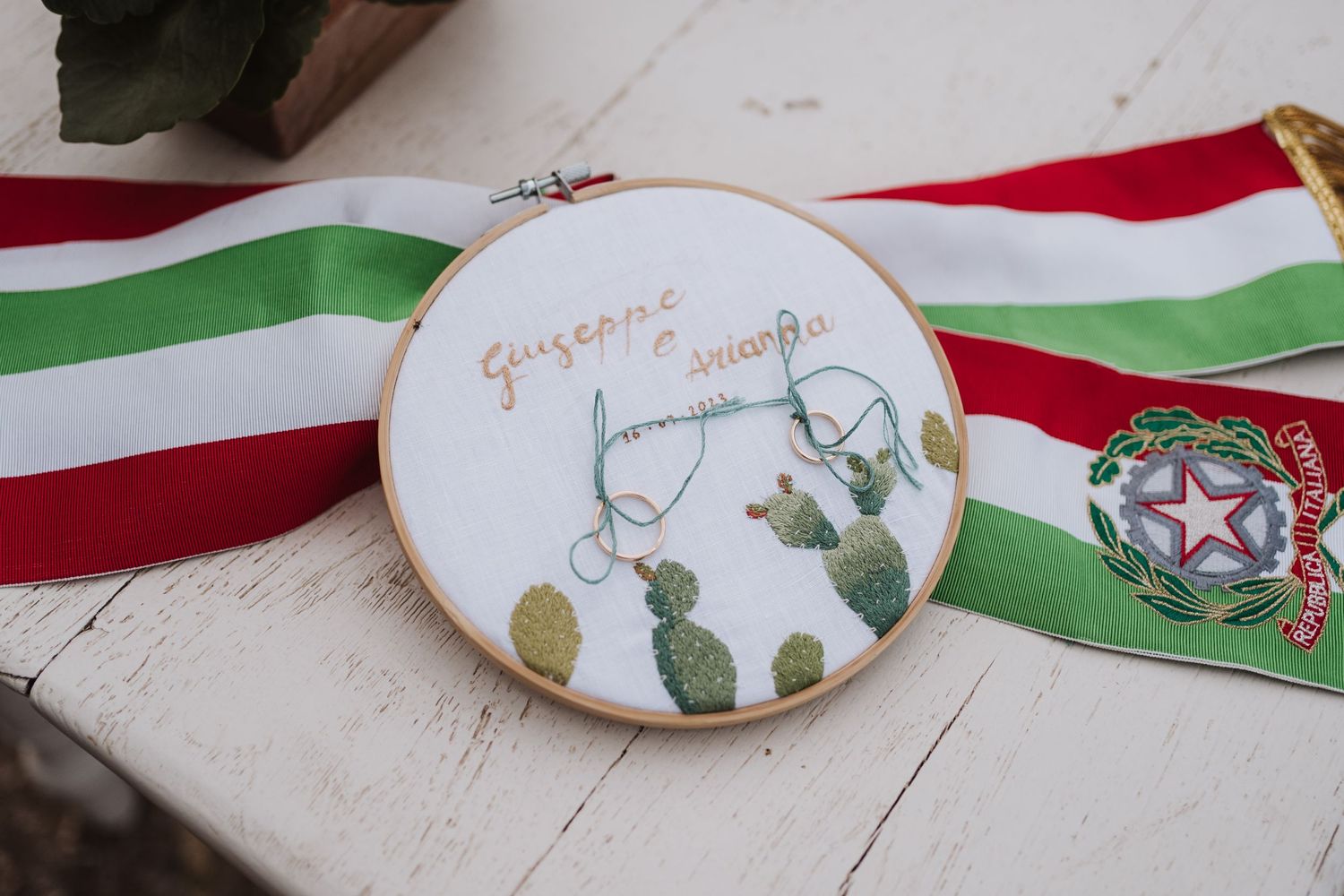 An embroidery hoop with Italian flag colors and cactus design on white surface.