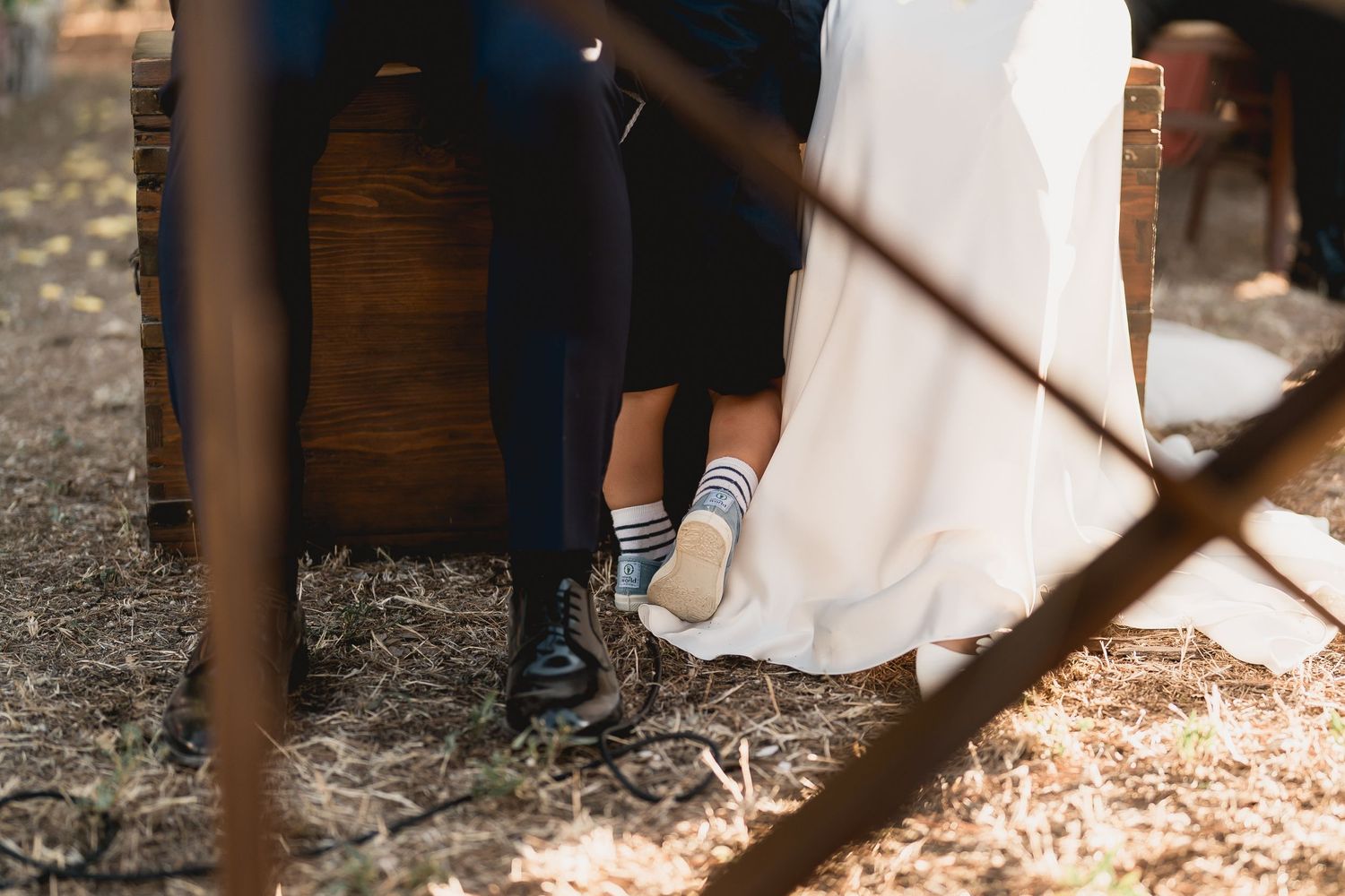 Close-up of bride and groom's feet showing contrasting formal shoes at outdoor wedding.