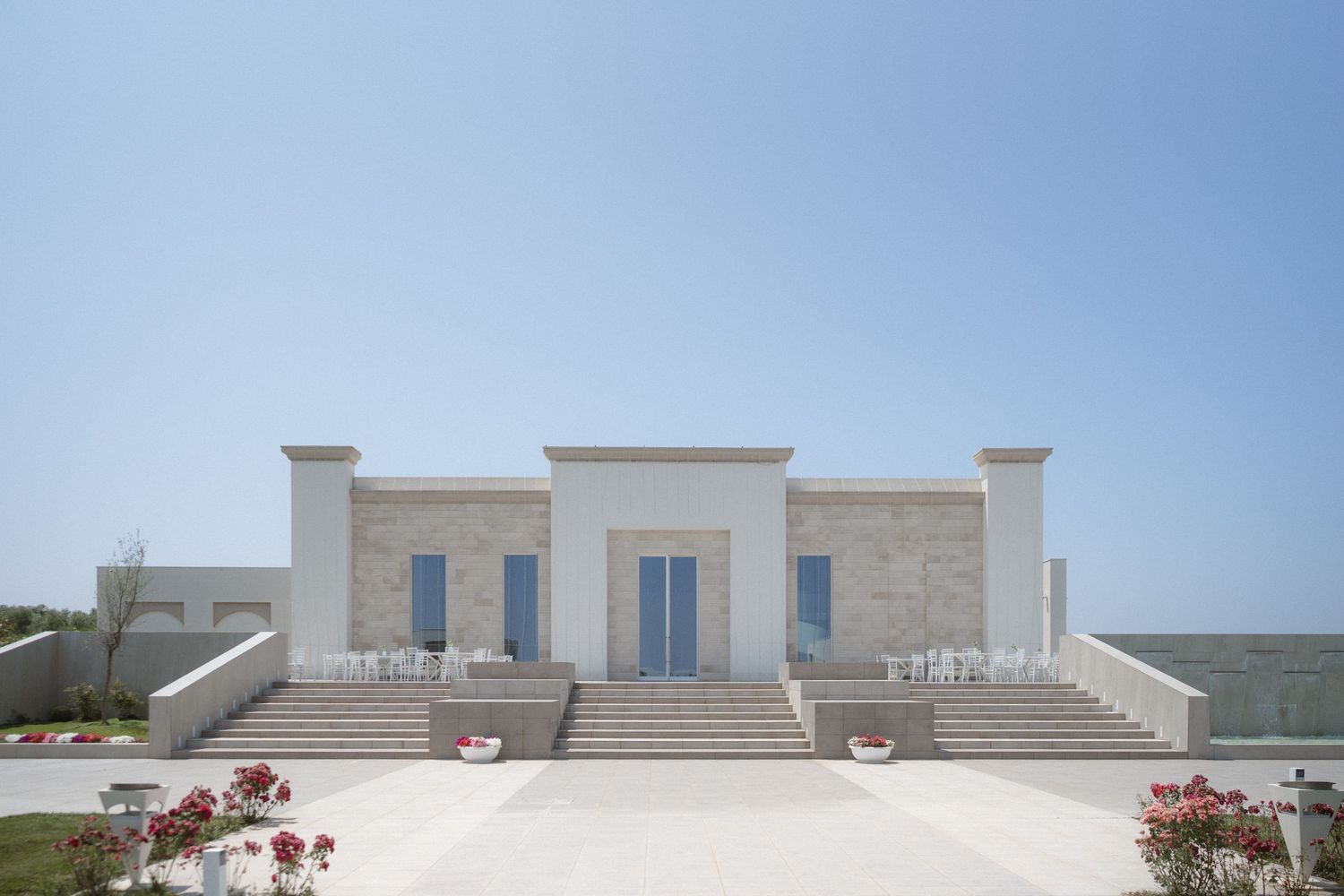 Modern white stone buildings against a clear blue sky in a Mediterranean architectural style.