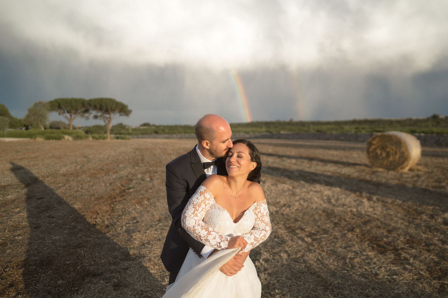 Wedding couple embracing in outdoor photos with dramatic cloudy sky.