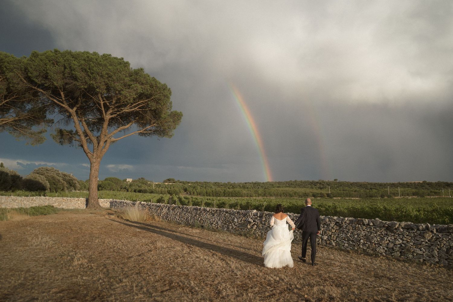 Dramatic landscape with rainbow appearing over stone walls and countryside.