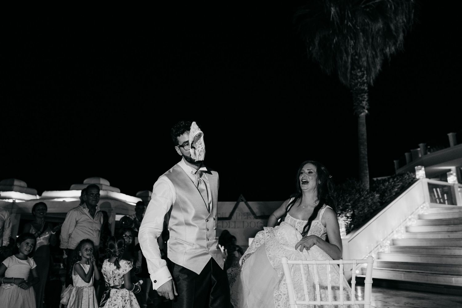 Black and white wedding reception scene with people dancing and celebrating.