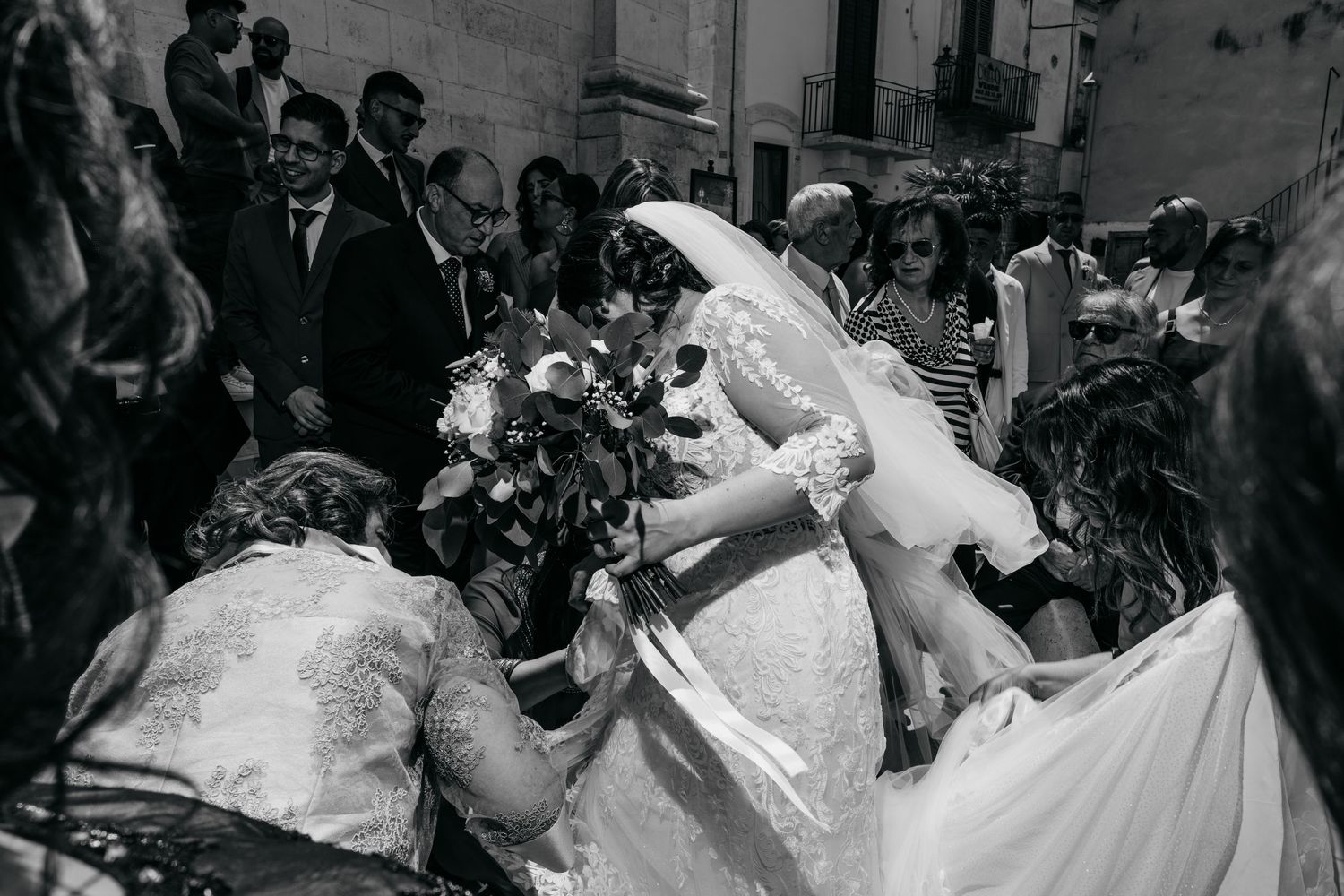 Black and white photo of a joyous wedding celebration with confetti being thrown at the couple.