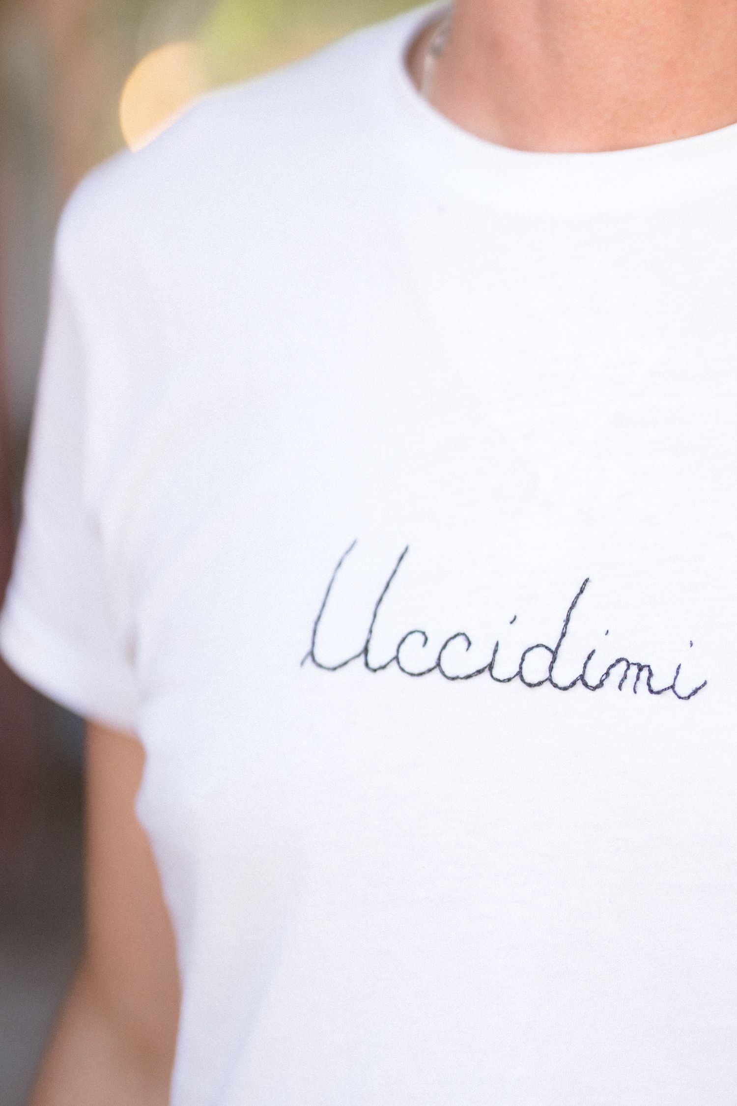 Close-up detail of handwritten text on a white t-shirt.