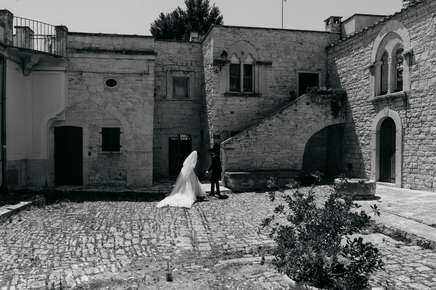 A black and white wedding photo in a cobblestone courtyard of an old stone building.