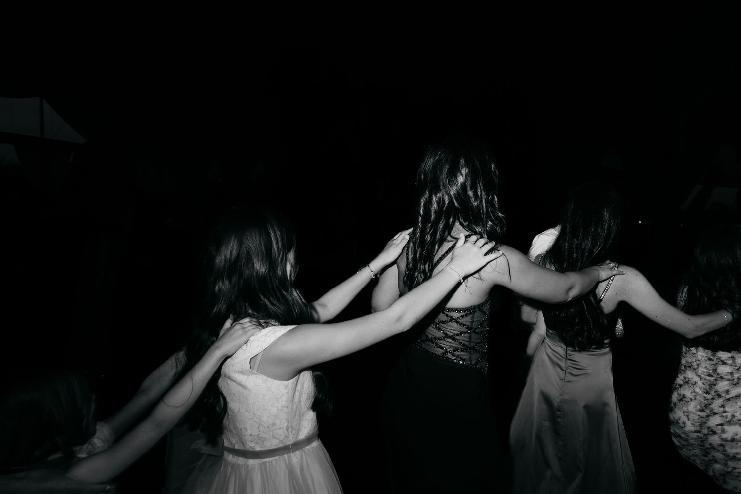 Black and white photo of people dancing in a circle at night event.