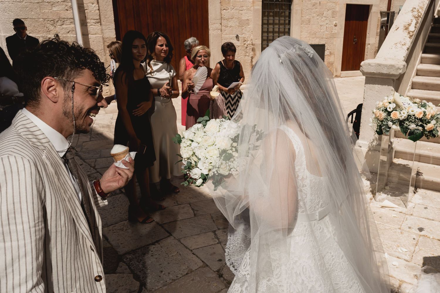 Wedding guests gather outside a historic stone church during a celebration.