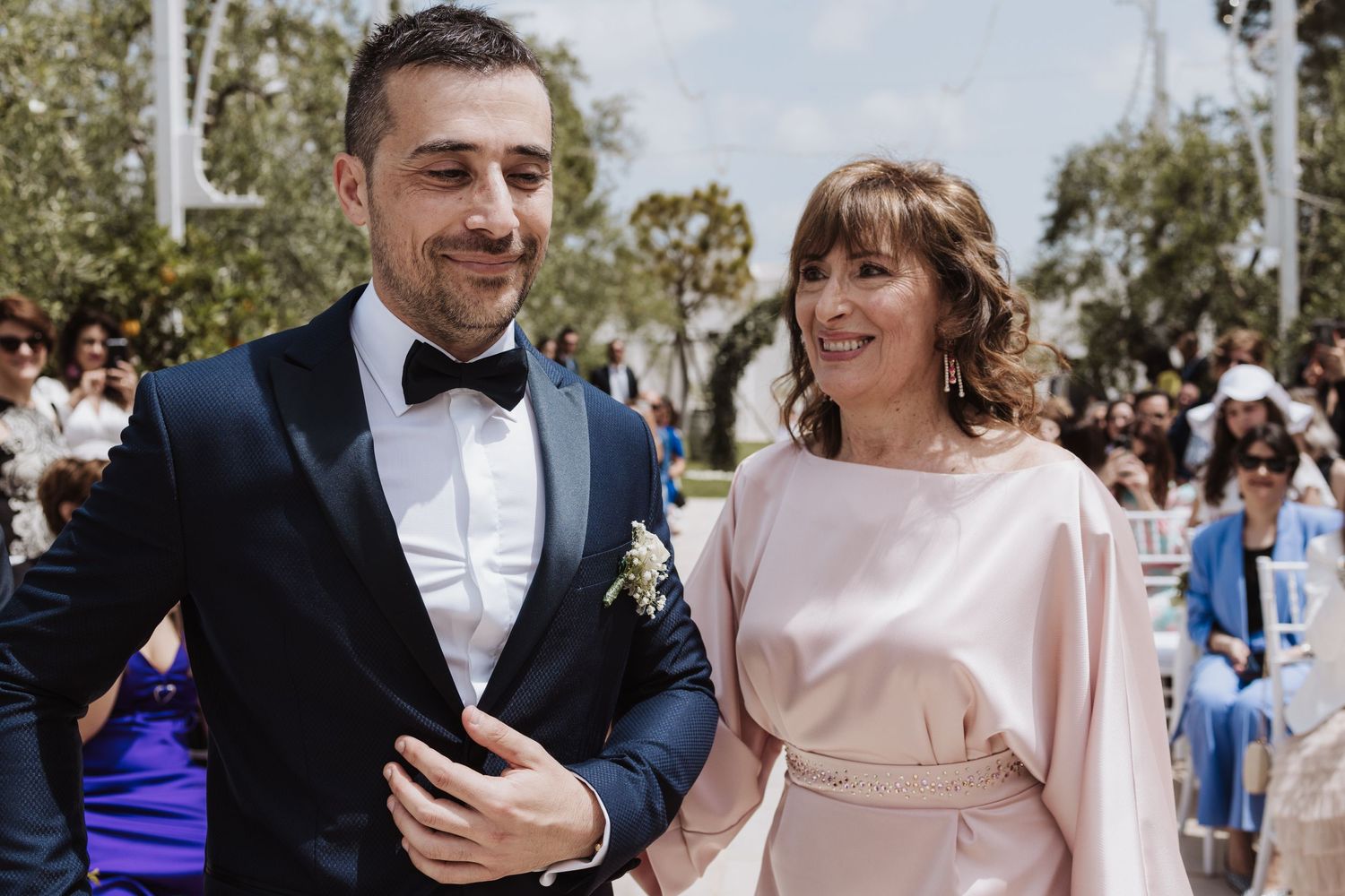 Couple walks together at outdoor wedding wearing formal attire.