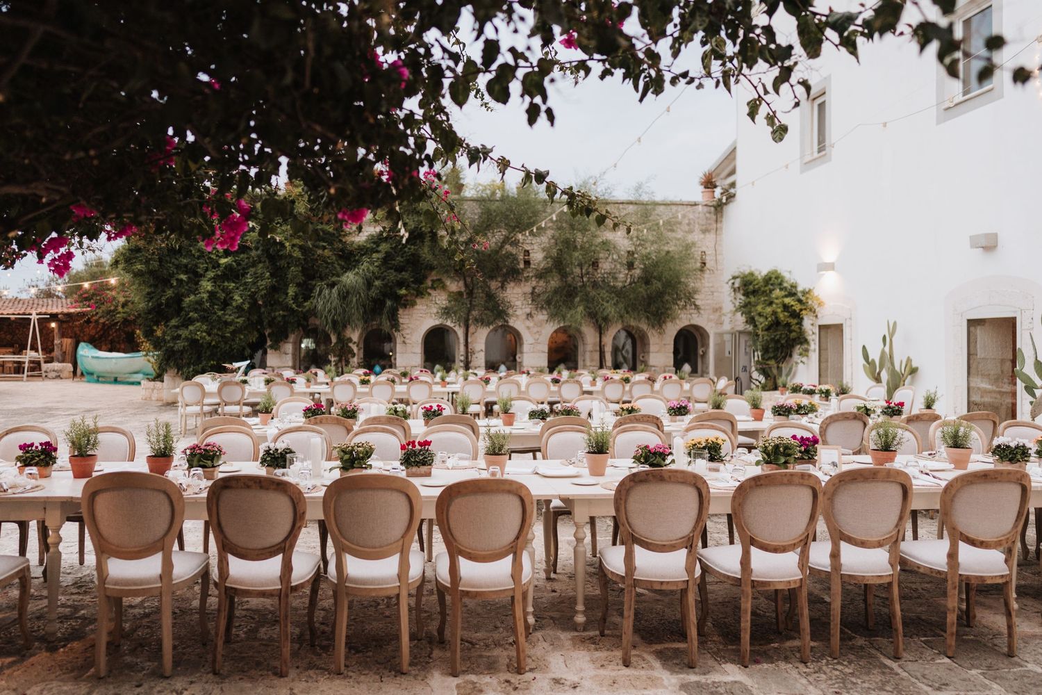 Elegant outdoor wedding reception setup with wooden chairs and tables at a Mediterranean venue.