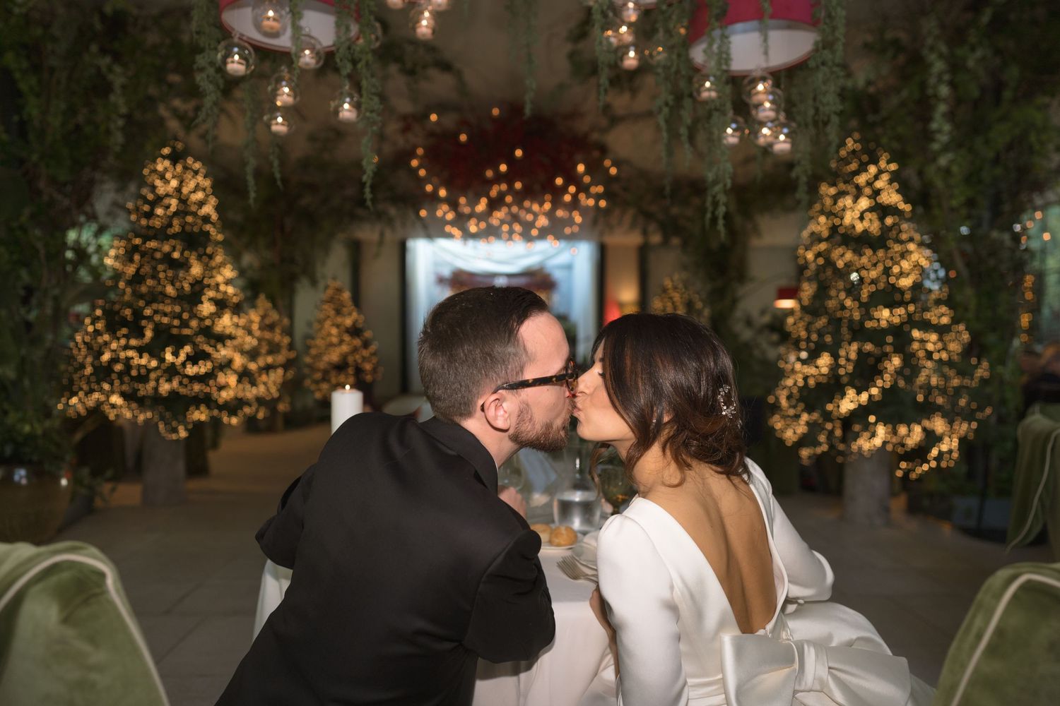 Bride and groom sharing a kiss at a festively decorated wedding reception.