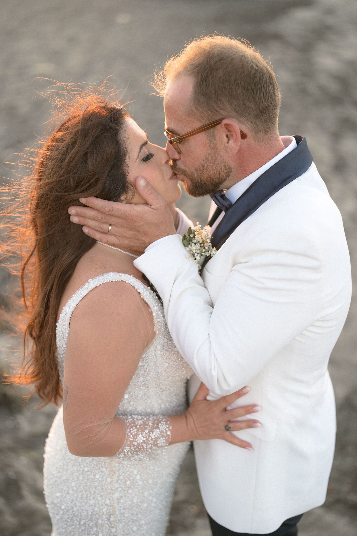 Intimate wedding portrait of couple sharing a kiss against sunset backdrop.