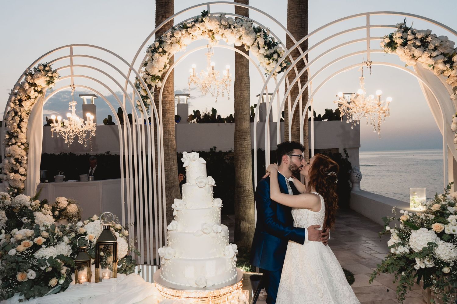 Elegant wedding ceremony setup with floral arches and chandeliers overlooking the ocean.