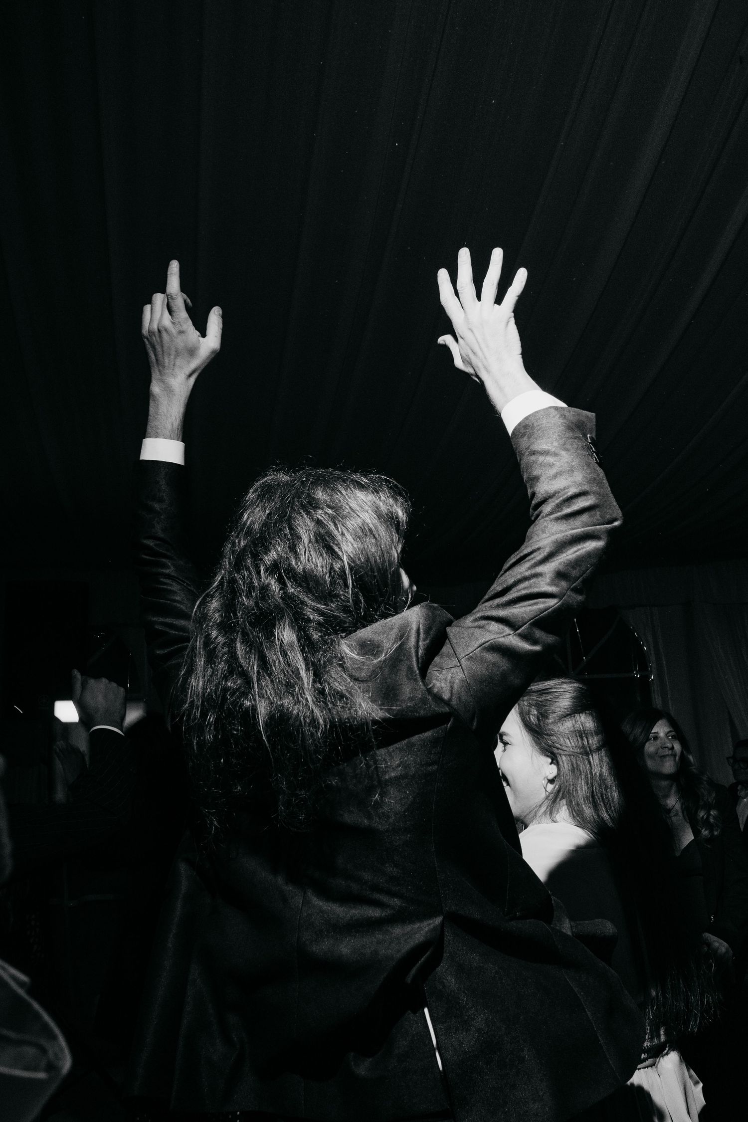 Silhouetted figures raise their hands in celebration on a dark dance floor.