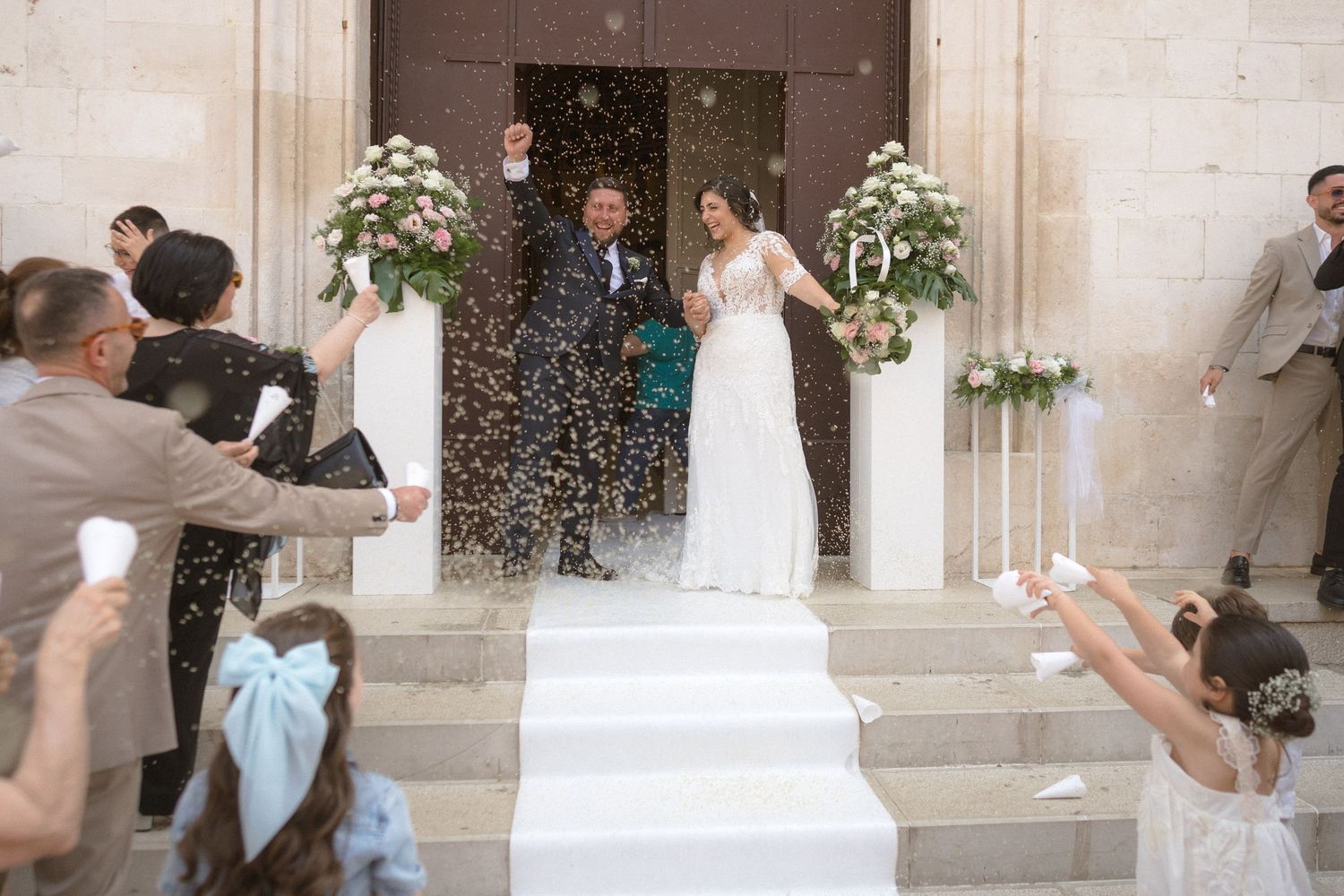 Wedding celebration with confetti being thrown outside a historic stone church.