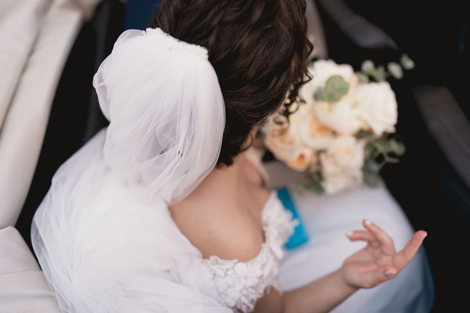 Wedding veil detail with soft focus bouquet in background.