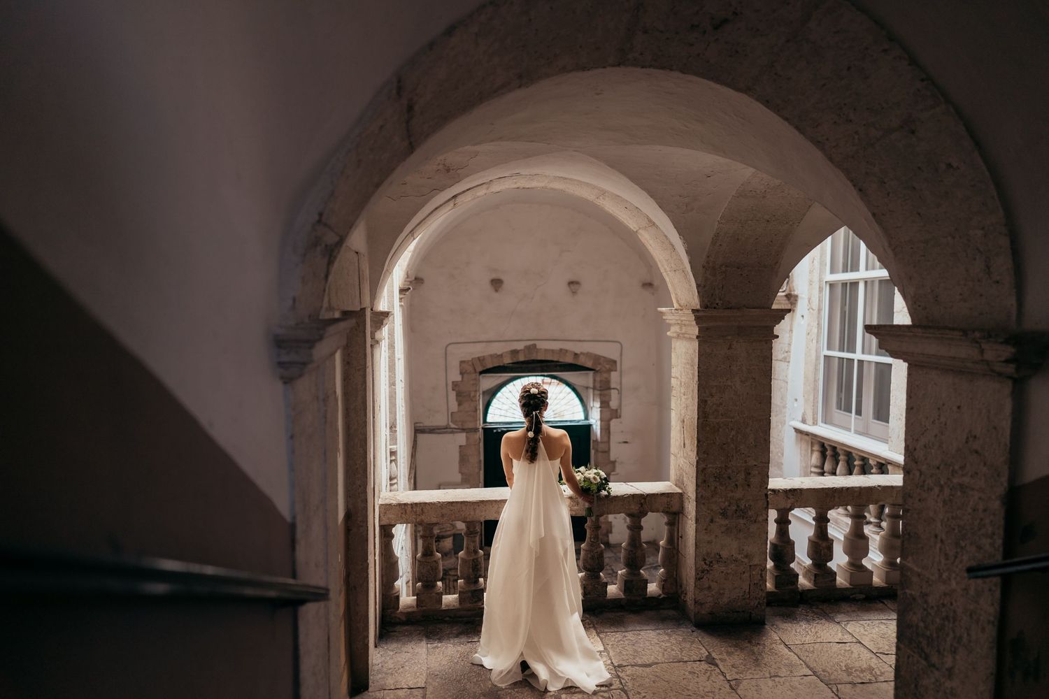A silhouette framed by stone archways in a historic building.