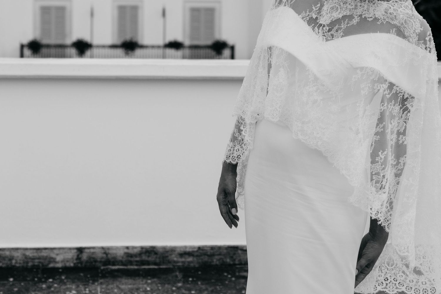 Black and white photograph showing side view of wedding dress with lace details.