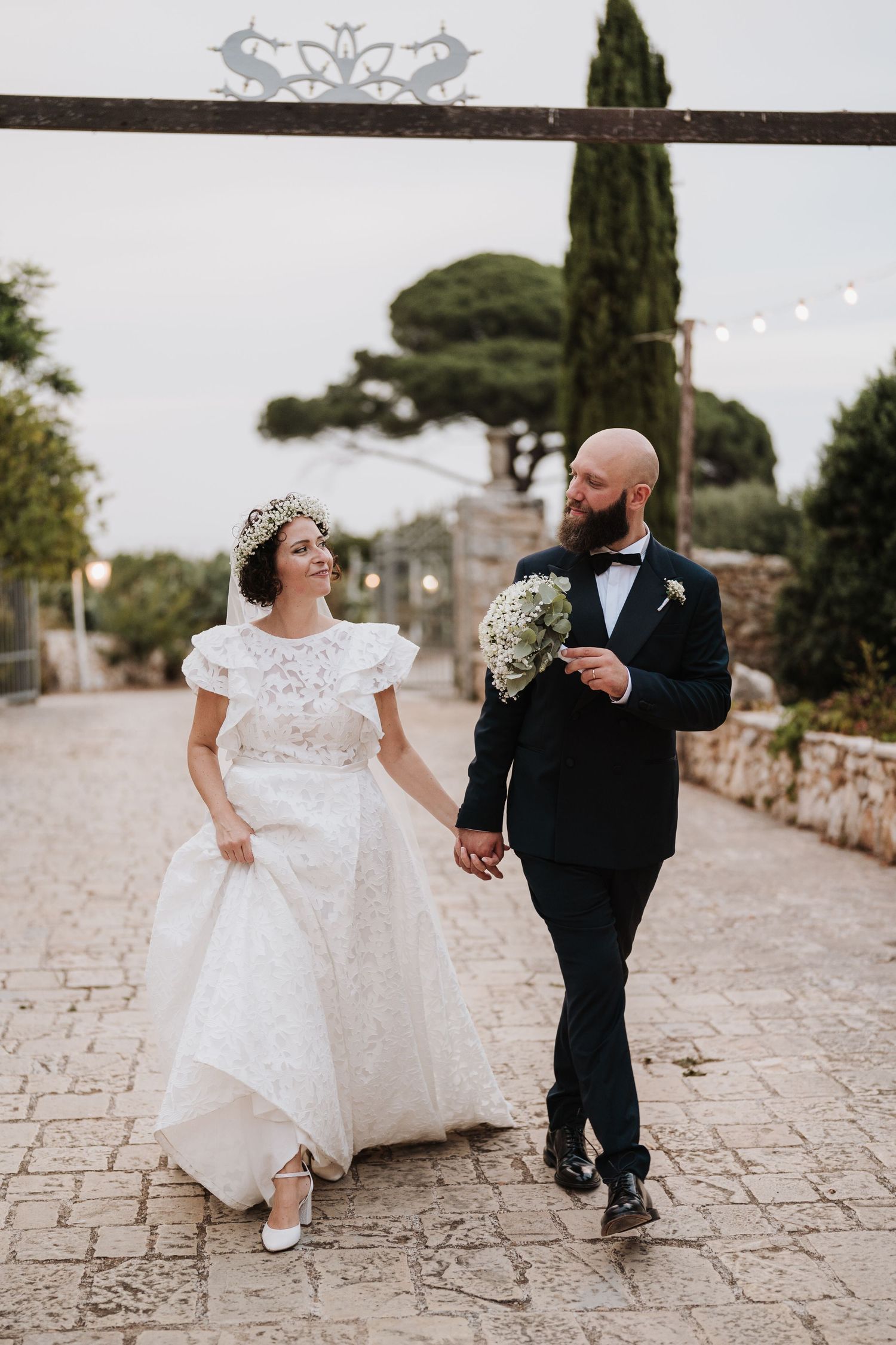 A joyful wedding moment captured on a stone pathway with string lights overhead.