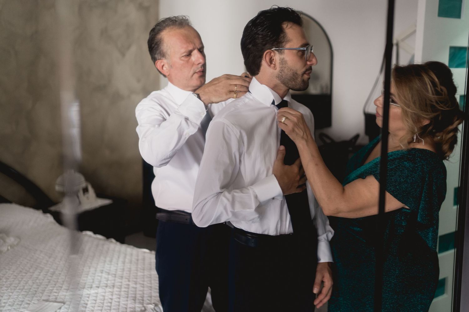 Wedding preparations as guests help adjust formal attire.