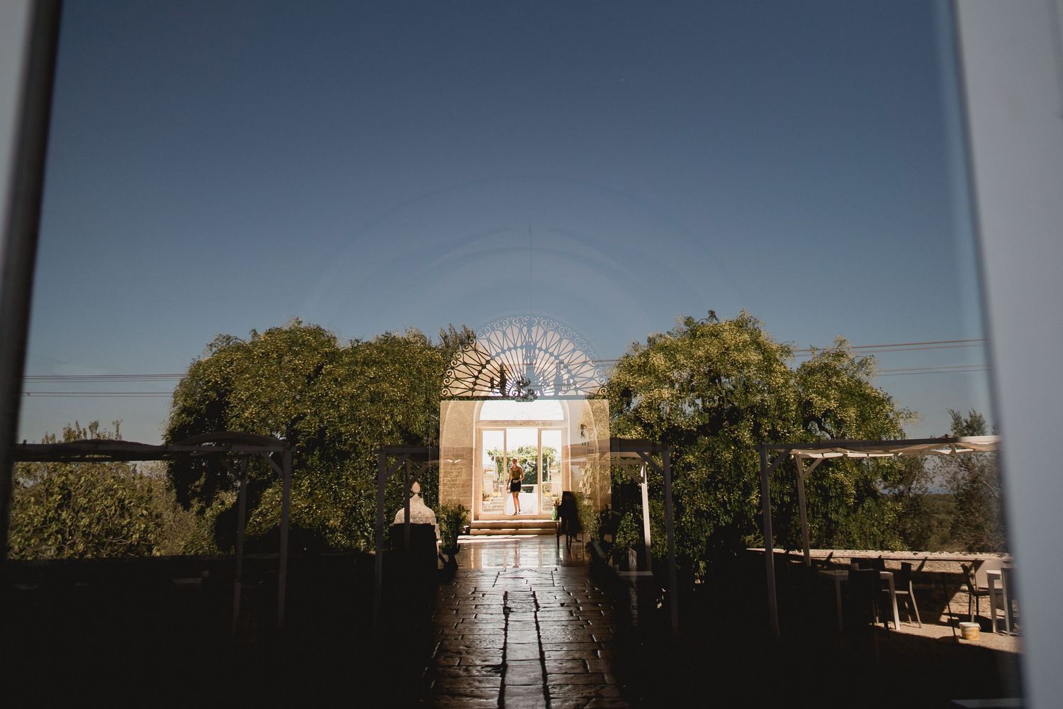 A wedding ceremony setup with white chairs leading to an ornate altar against a blue sky.