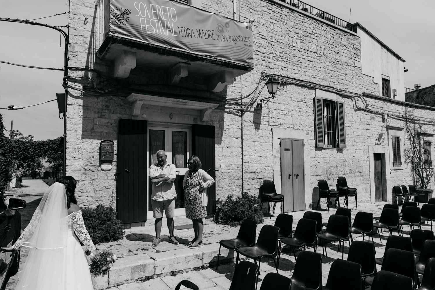 Black and white exterior view of wedding venue with guests arriving.