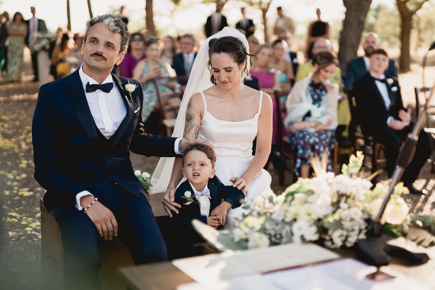 Wedding ceremony outdoors with guests watching as couple signs marriage documents.