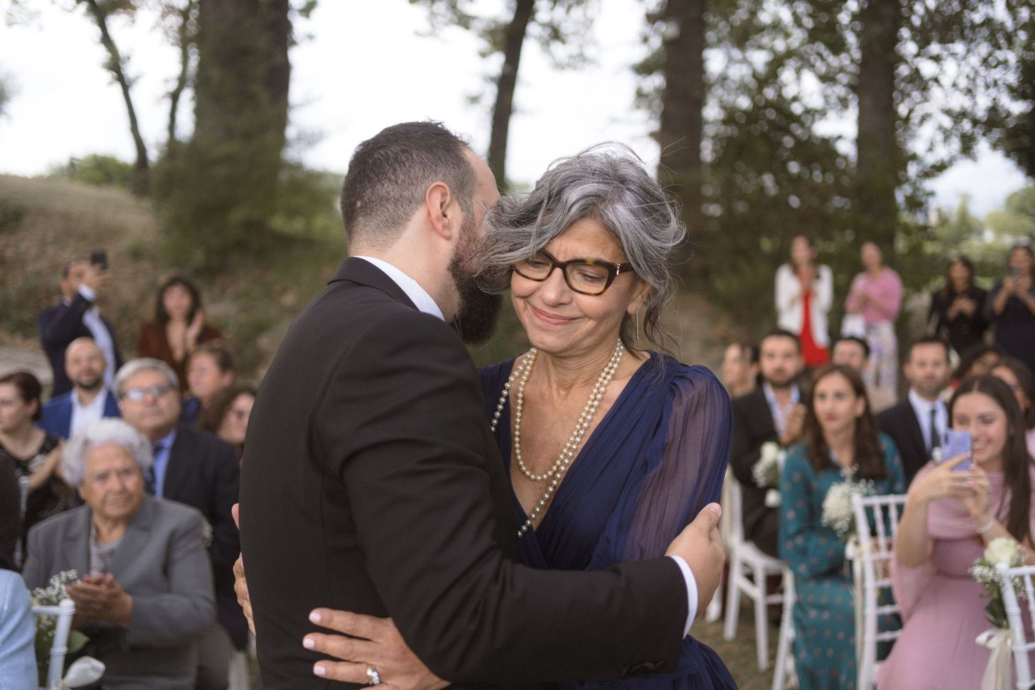 Wedding guests dancing and embracing during an outdoor celebration.