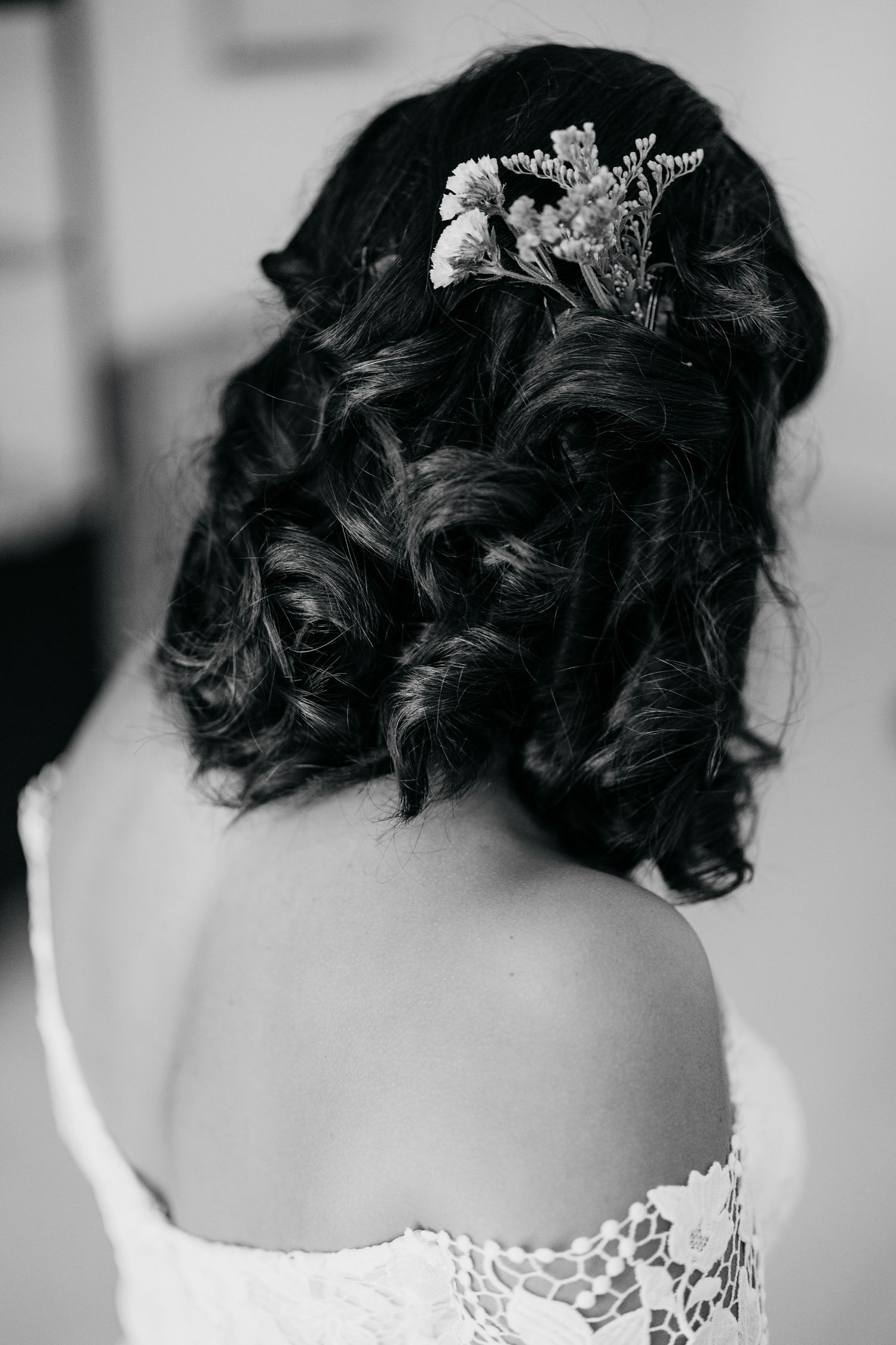 Elegant bridal hairstyle shown from behind with dark curls and delicate hair accessories.