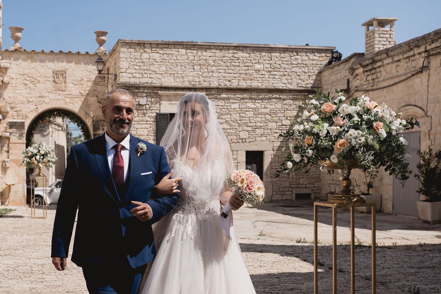 A wedding ceremony entrance at a historic stone building with floral decorations.