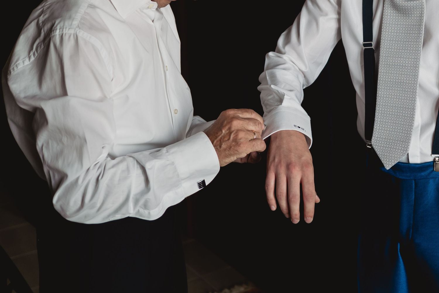 Close-up of hands adjusting formal white shirt cuffs and buttons.