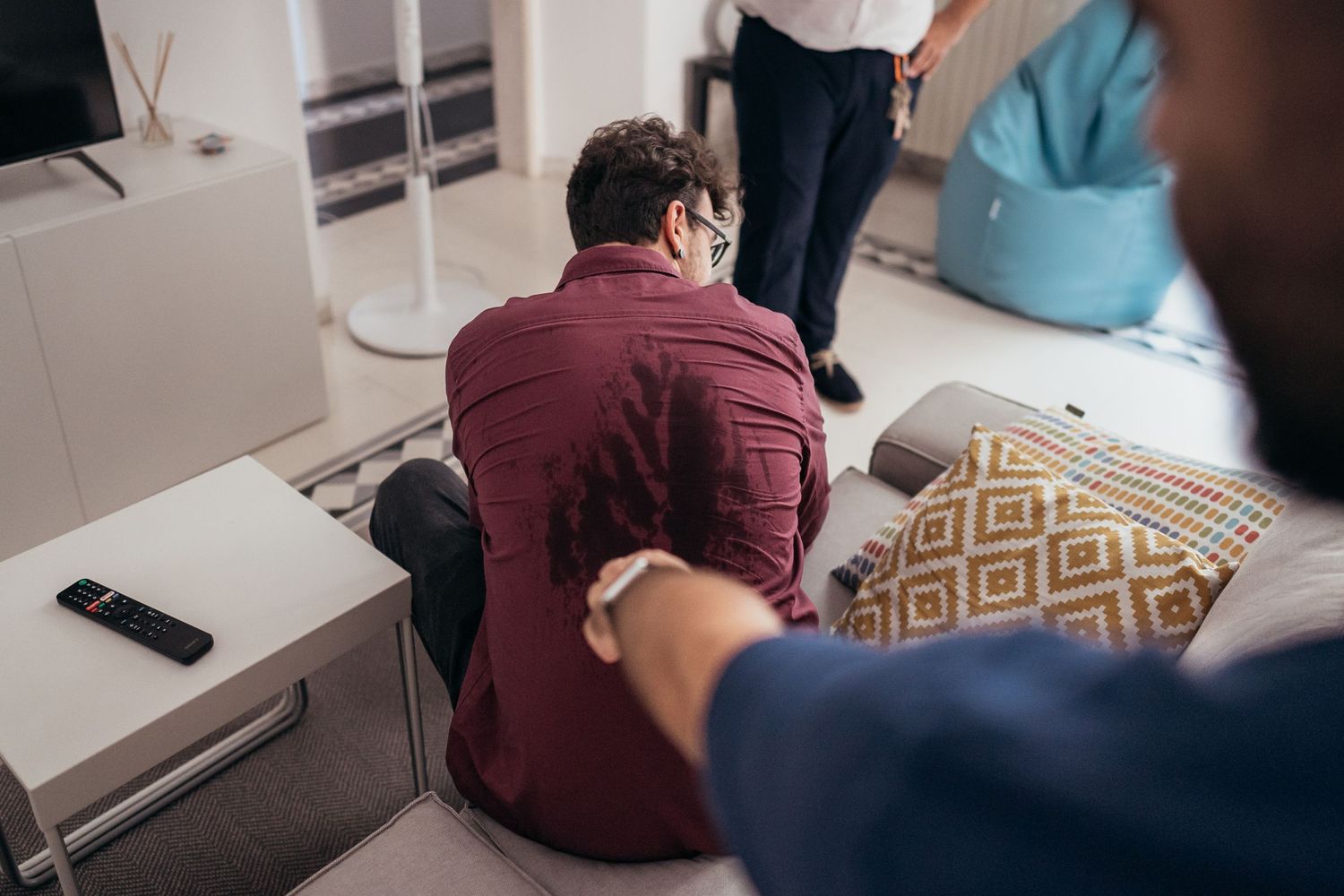 People gathered in a casual living room setting with patterned throw pillows.