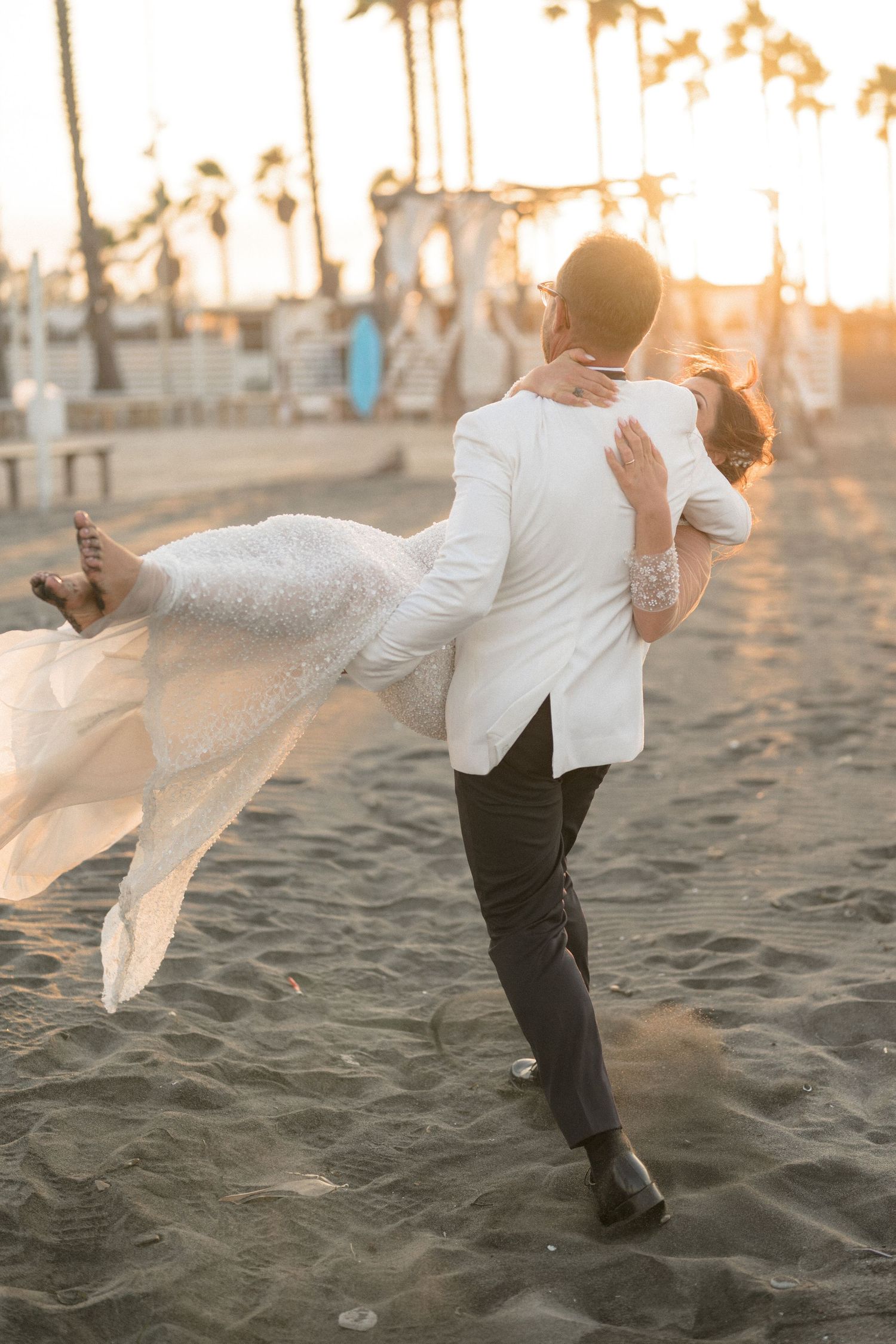 Romantic beach wedding photo of couple dancing at sunset with flowing white dress.