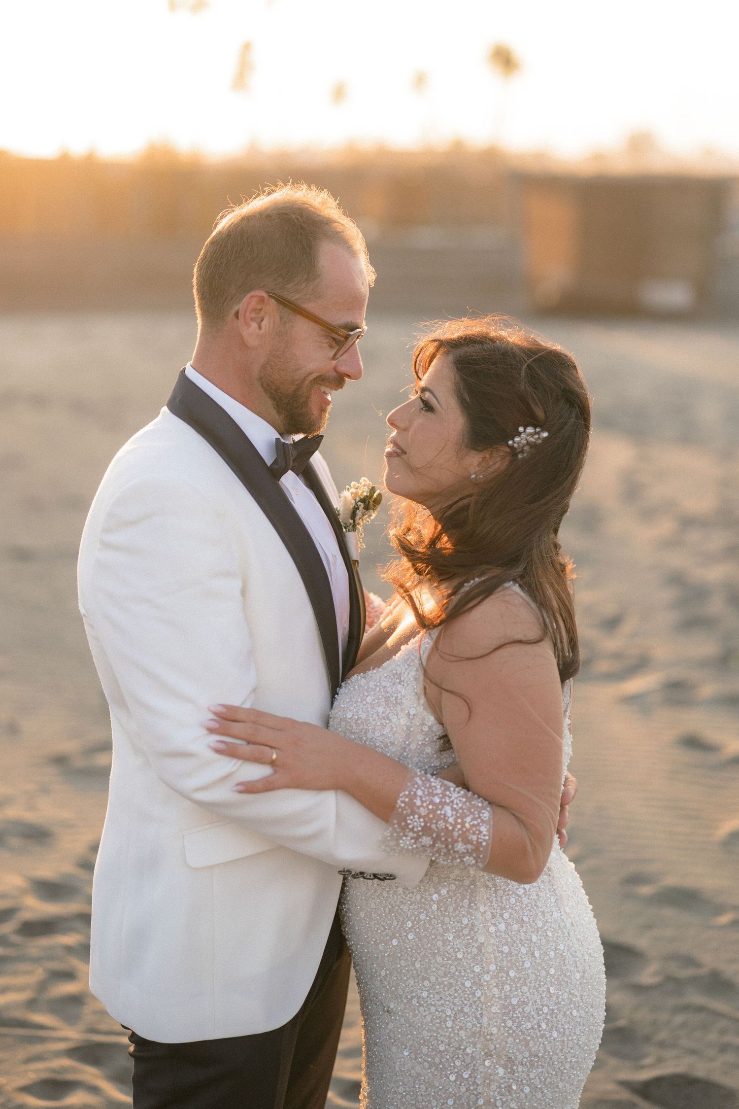 Romantic sunset beach portraits of newlyweds in formal attire.