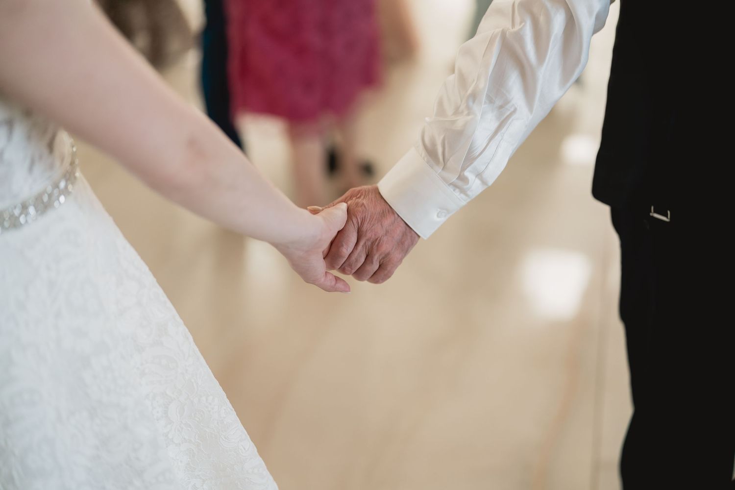 Close-up of joined hands during a wedding ceremony against a white background.