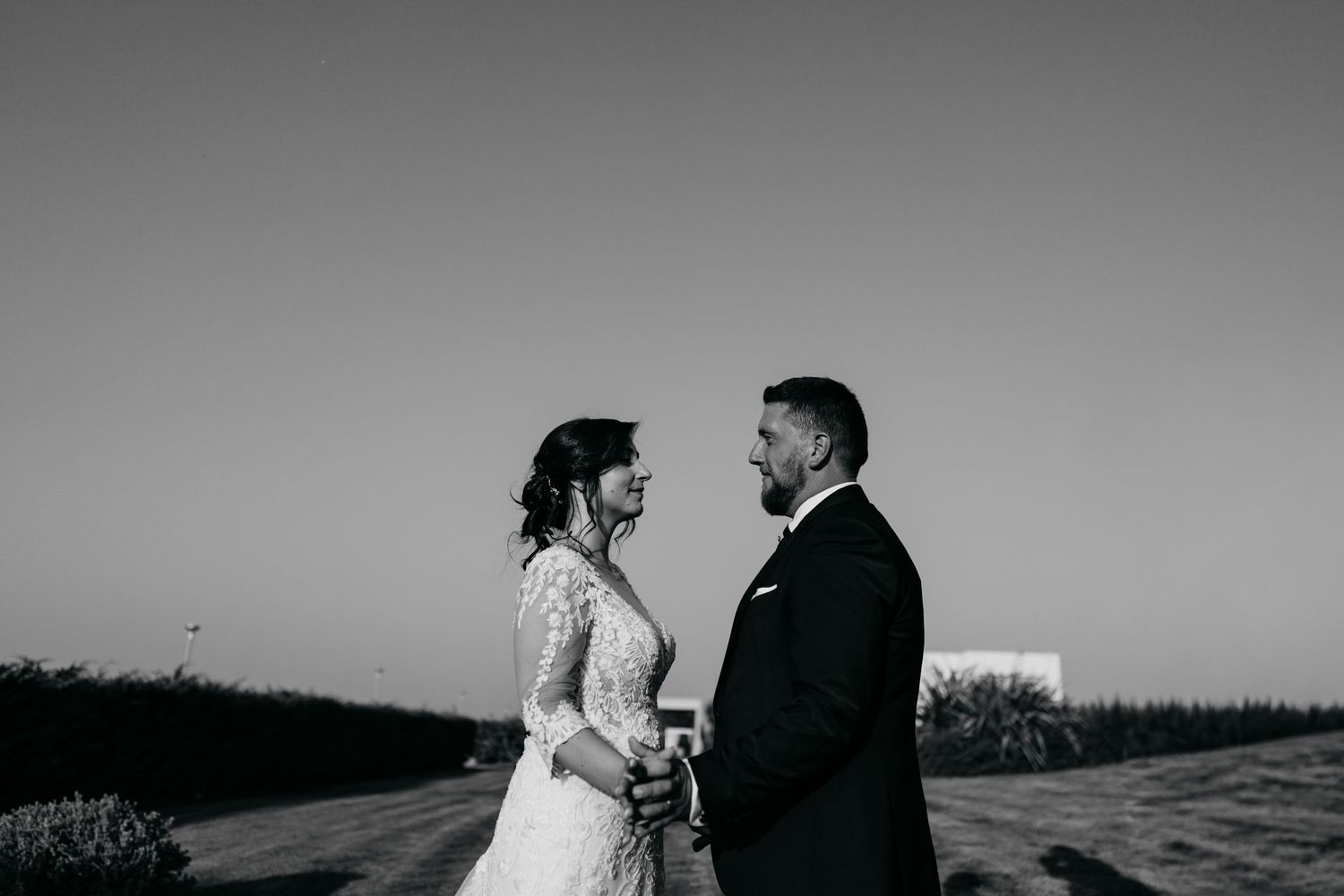 Dramatic black and white silhouettes of a couple embracing on a hilltop at sunset.