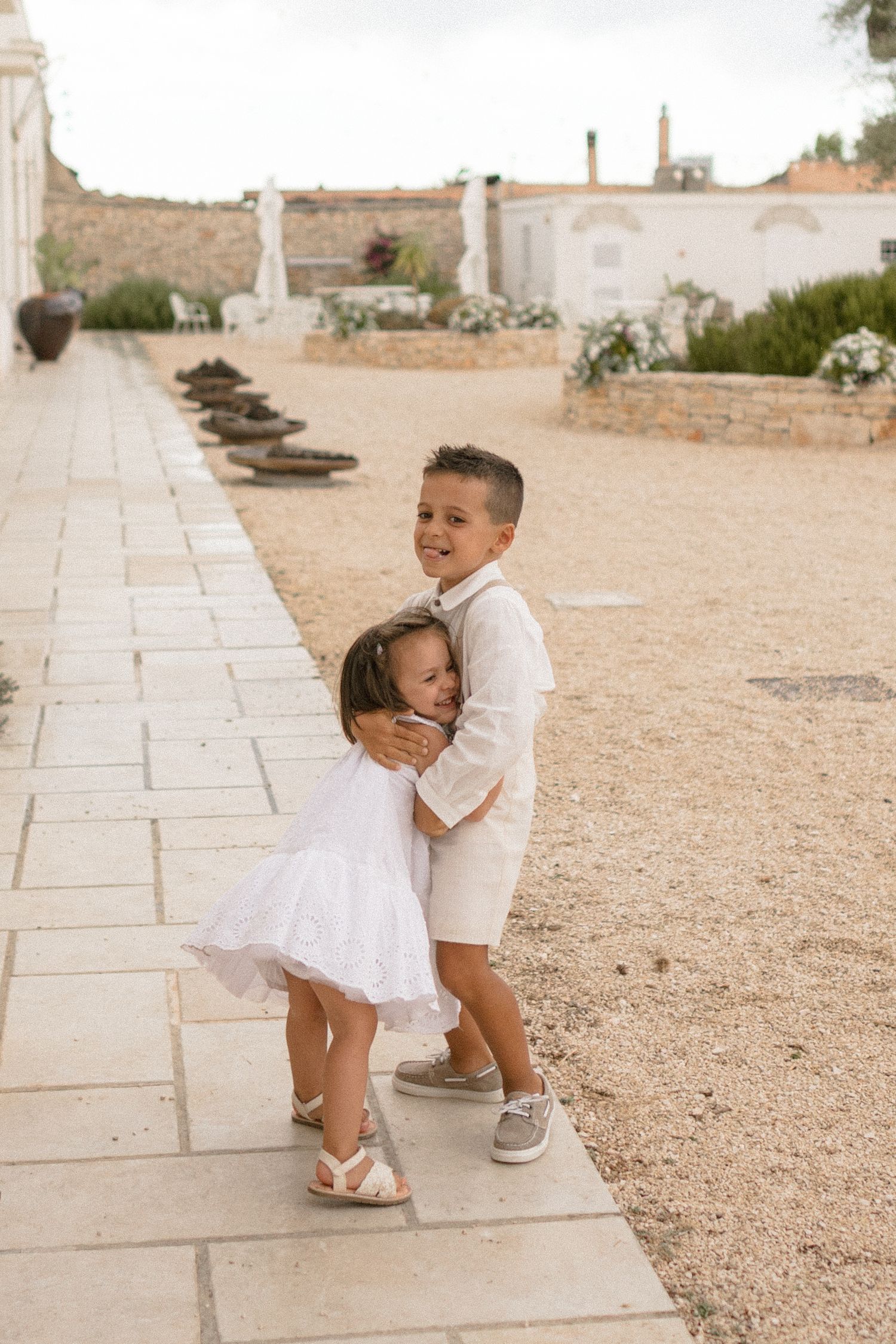 Playful sequence of children in white outfits playing on stone pathways.