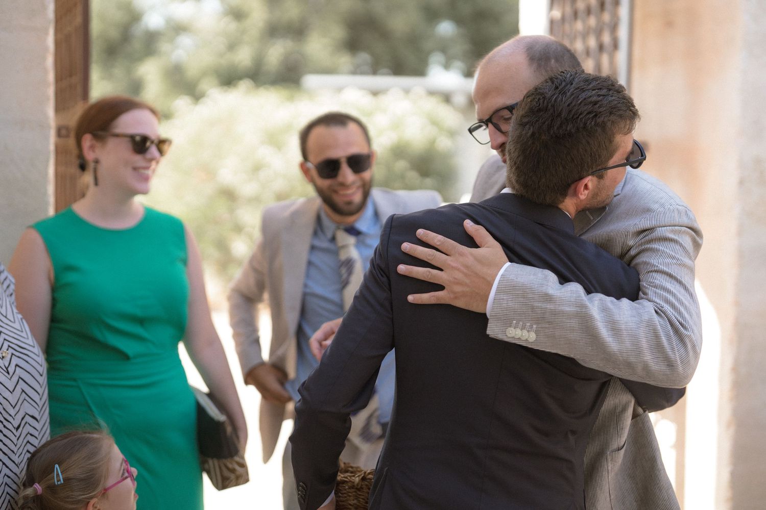 Wedding guests embrace and celebrate during an outdoor reception.
