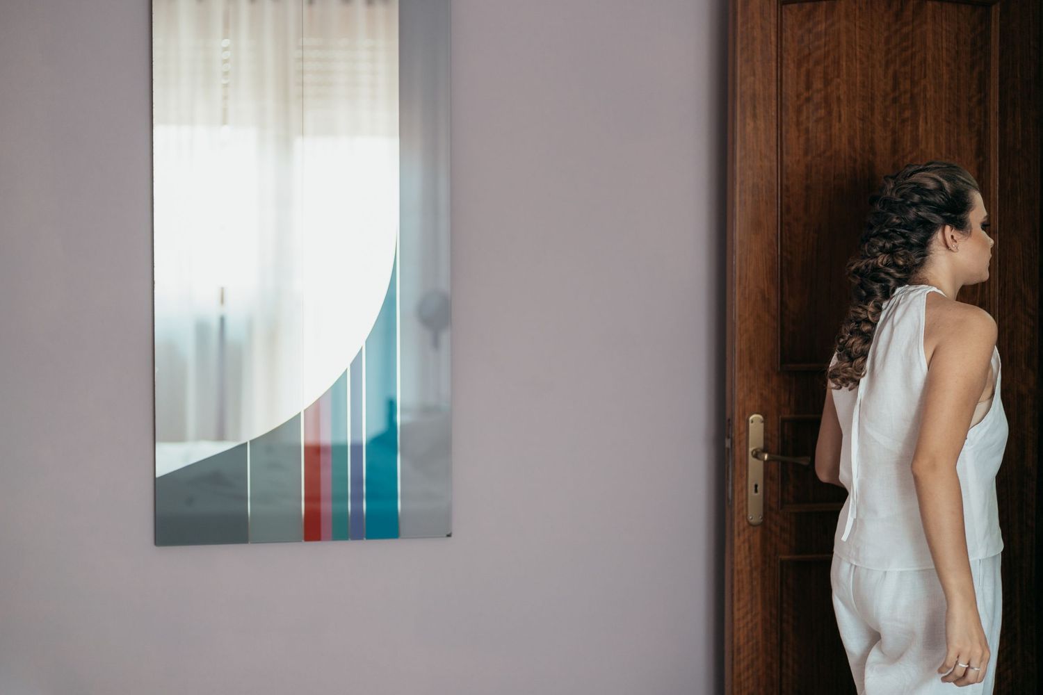 An elegant white dress is shown next to abstract wall art in a minimalist interior setting.