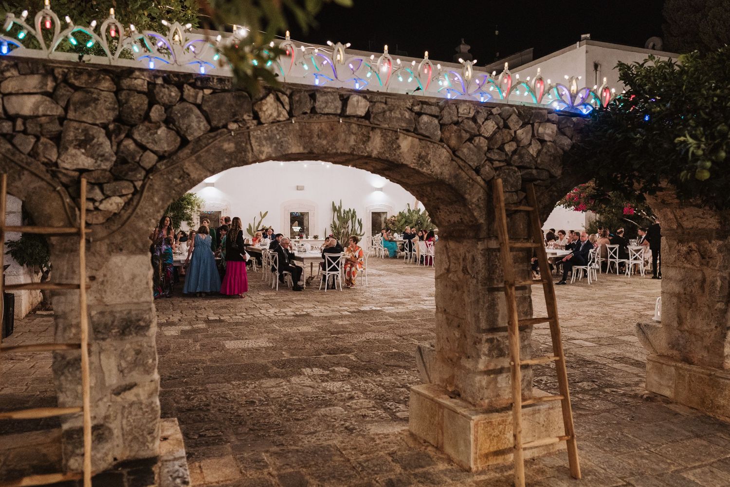 Reception area under stone archway with colorful lights and guest tables.